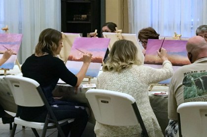 Participants painting at a past "Snowy Morning" paint and sip